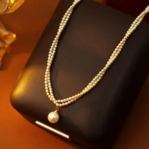 Detailed close-up of a double-layer small pearl necklace with a large pearl pendant.