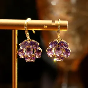 Detail shot of elegant purple gemstone cluster earrings on a gold display stand.