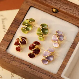 Detail of three pairs of colorful wave-shaped enamel earrings in a vintage wooden jewelry box