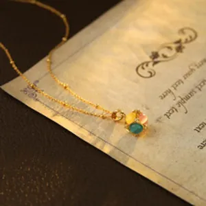 Detailed macro view of a delicate gold necklace with a vibrant colorful gemstone pendant