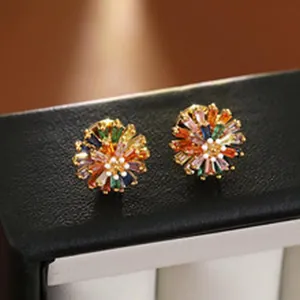 Close-up of colorful zircon flower stud earrings displayed on a black jewelry box edge