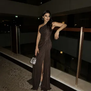 Detailed view of brown one-shoulder pleated evening gown with high slit