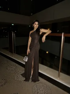 Elegant brown one-shoulder pleated evening gown paired with a sparkling silver handbag