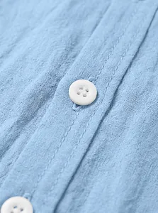 Détail d'une chemise homme en coton et lin bleu montrant le bouton blanc et la texture