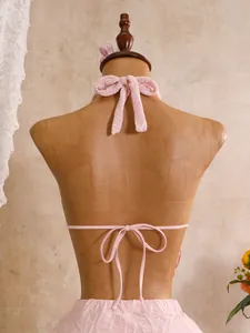 Detailansicht der Rückenschnürung und Textur eines hellrosa dreiteiligen Bikini-Oberteils.