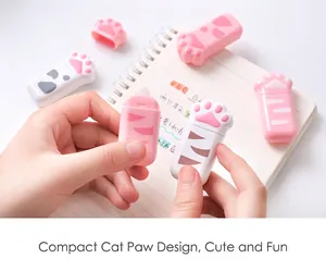 Close-up of cute cat paw shaped correction tapes held in hands over a notebook