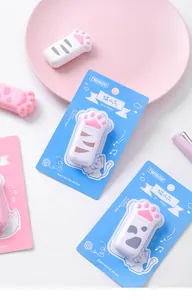 Close-up detail of cute cat paw shaped correction tape with blue card packaging and pink saucer