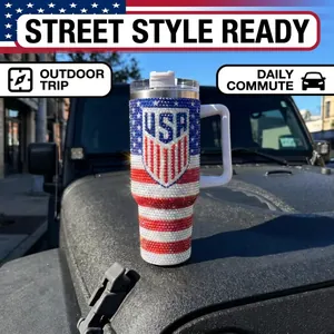 Close-up of 40oz rhinestone tumbler with USA flag and shield design on a car hood.