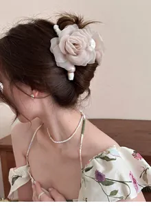 Vue détaillée d'une pince à cheveux rose en résille avec perles dans un chignon chic