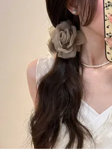 Gros plan d'une pince à cheveux rose en tulle sur cheveux bruns ondulés.
