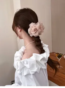 Détail d'une pince à cheveux rose en tulle sur une coiffure tressée