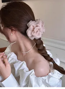Vue détaillée d'une pince à cheveux fleur rose en tulle sur tresse avec perles