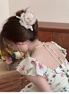 Détail d'une pince à cheveux rose en tulle avec des perles sur un chignon bas.