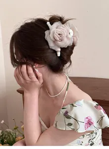 Vue détaillée d'une pince à cheveux élégante avec roses en résille et perles sur chignon.