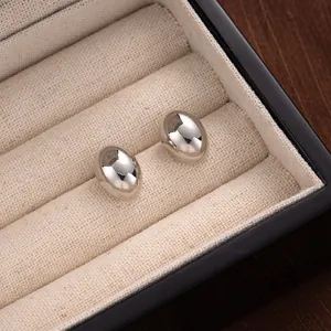 Minimalist mirror polished silver oval bean stud earrings displayed in a jewelry box