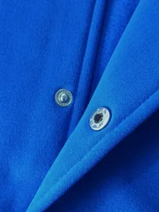 Macro detail shot of the silver metal snap buttons on a blue fleece-lined baseball jacket.