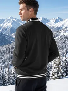 Back view of men's black baseball jacket with white stripes in snowy mountain landscape