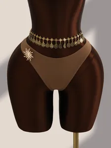 Détail d'une broche soleil dorée et d'une chaîne de taille sur un bikini marron