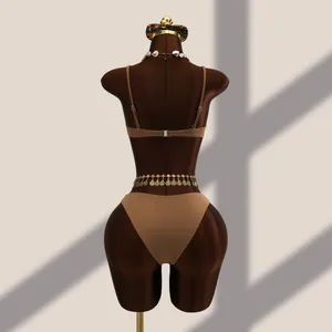 Vue arrière d'un ensemble bikini marron sur un mannequin avec accessoires dorés de plage.