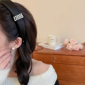 Close-up of a stylish wide black fabric headband with elegant pearl accents on a model