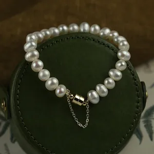 Elegant white pearl bracelet with a golden magnetic clasp and safety chain detail.