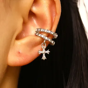 Close-up detail of a silver double-row cross ear cuff with sparkling zircons on an ear.