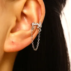 Macro detail of silver cross ear cuff with sparkling zircon and a delicate chain