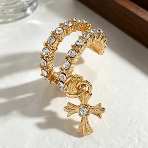 Close-up of gold-plated zircon-inlaid cross ear cuff with dangling charm.