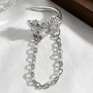 Detailed view of elegant silver cross ear cuff with chain and cubic zirconia