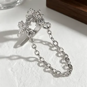 Detailed macro shot of silver-toned zircon cross ear cuff featuring a delicate metal chain