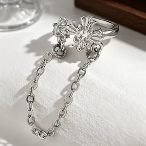 Close-up detail of silver-tone cross ear cuff with hanging chain and sparkling zircon stone