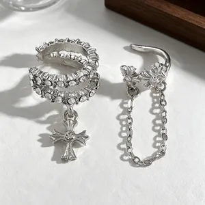 Close-up of silver-toned cross ear cuff with zircon inlay and hanging chain detail