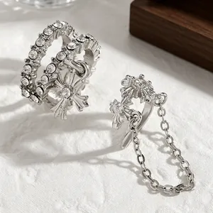 Macro detail of silver-colored cross ear cuffs with chain and sparkling zirconia stones.