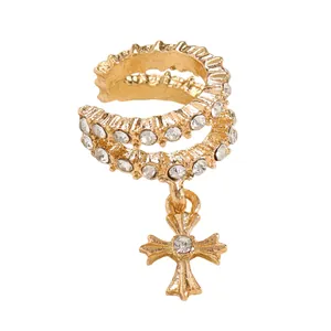 Macro detail of a gold copper ear cuff featuring zircon stones and a cross pendant