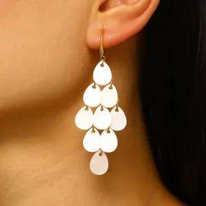 Gros plan de boucles d'oreilles à pompons en pétales d'acrylique blanc sur un modèle