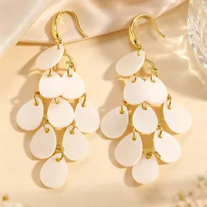Vue détaillée de boucles d'oreilles élégantes à pampilles en acrylique blanc et or