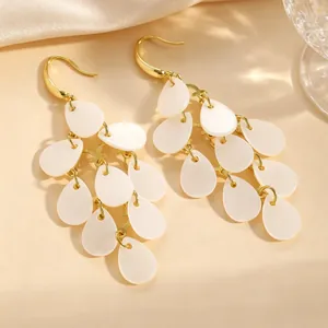 Gros plan d'élégantes boucles d'oreilles en acrylique blanc avec crochets dorés.