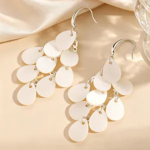 Détail macro d'élégantes boucles d'oreilles pompons en pétales d'acrylique blanc.