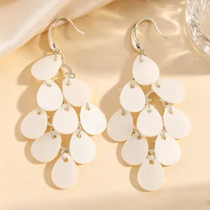 Gros plan sur d'élégantes boucles d'oreilles en pétales d'acrylique blanc à effet perlé.