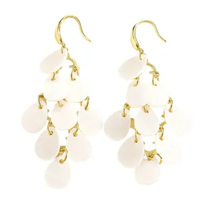 Gros plan d'élégantes boucles d'oreilles dorées avec glands en pétales d'acrylique blanc