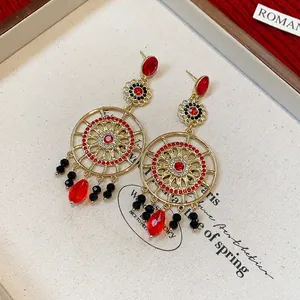 Détail de boucles d'oreilles vintage fleurs ajourées avec cristaux rouges et perles noires