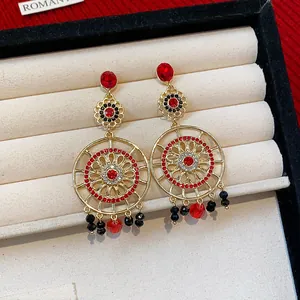 Gros plan détaillé de boucles d'oreilles pendantes ethniques avec strass rouges et noirs