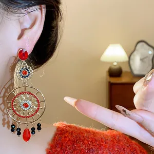 Gros plan sur des boucles d'oreilles ethniques vintage dorées à fleurs avec pierres rouges.