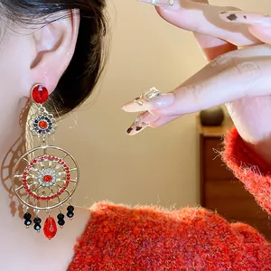 Détail de boucles d'oreilles ethniques vintage avec cristaux rouges et motif doré ajouré