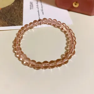 Nahaufnahme eines transparenten rosa Glasperlenarmbands auf minimalistischem Grund