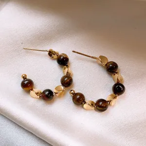 Vintage gold-plated Tiger Eye stone beaded hoop earrings presented on cream silk fabric