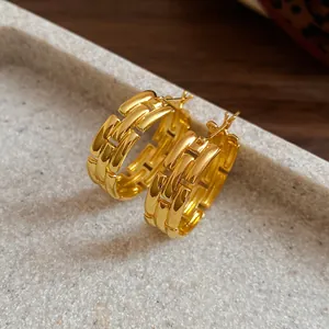 Detailed close-up of gold-plated hoop earrings with a stylish chunky woven link design