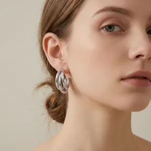 Close-up of stylish stainless steel triple hoop earrings worn on a model's ear