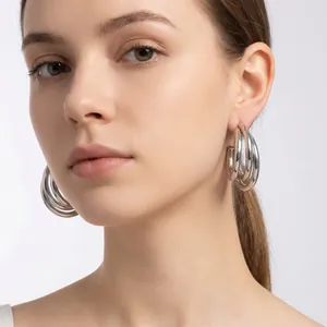 Close-up of minimalist stainless steel triple hoop C-shaped earrings on model.