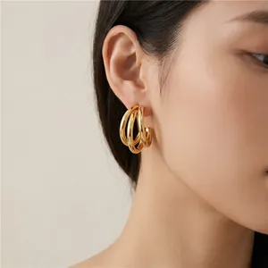 Close-up view of elegant gold triple layered C-shaped stainless steel hoop earrings